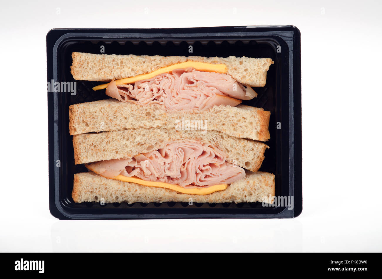 Takeaway  prepared smoked turkey and cheese sandwich on wheat bread in a black packet on white background Stock Photo
