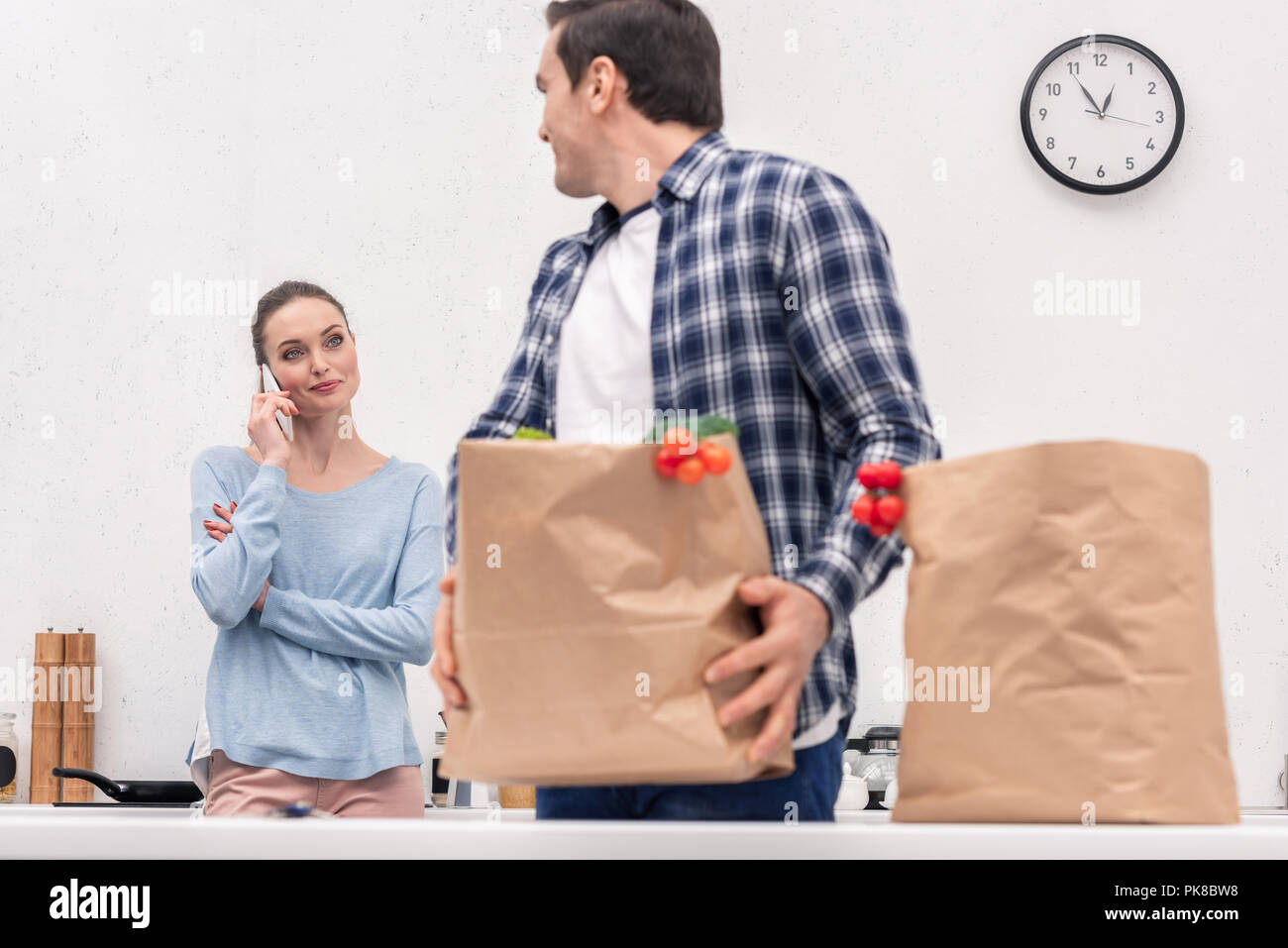 adult man carrying paper bag from grocery store while his wife talking by phone Stock Photo