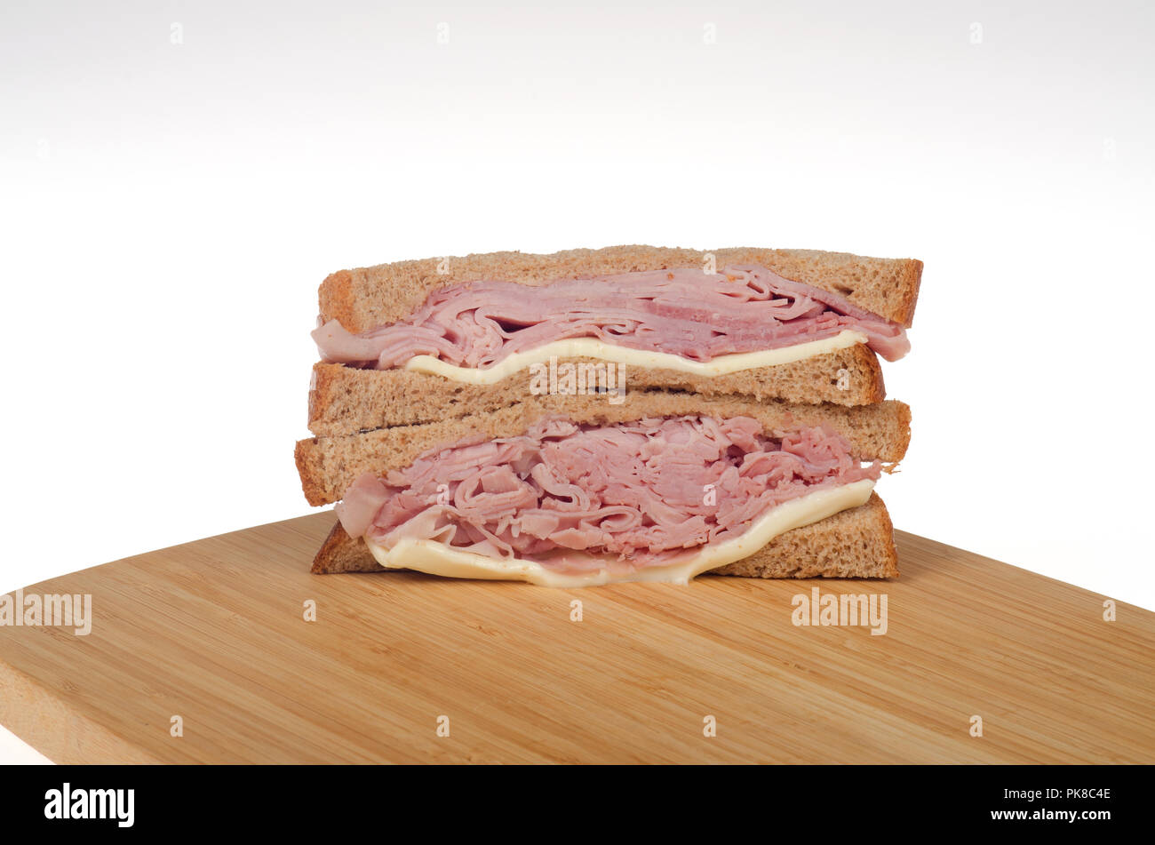 Ham and Cheese sandwich on whole wheat bread on a wood cutting board Stock Photo