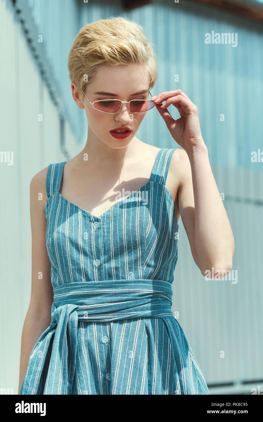 stylish girl with short hair posing in trendy blue dress and pink  sunglasses Stock Photo - Alamy