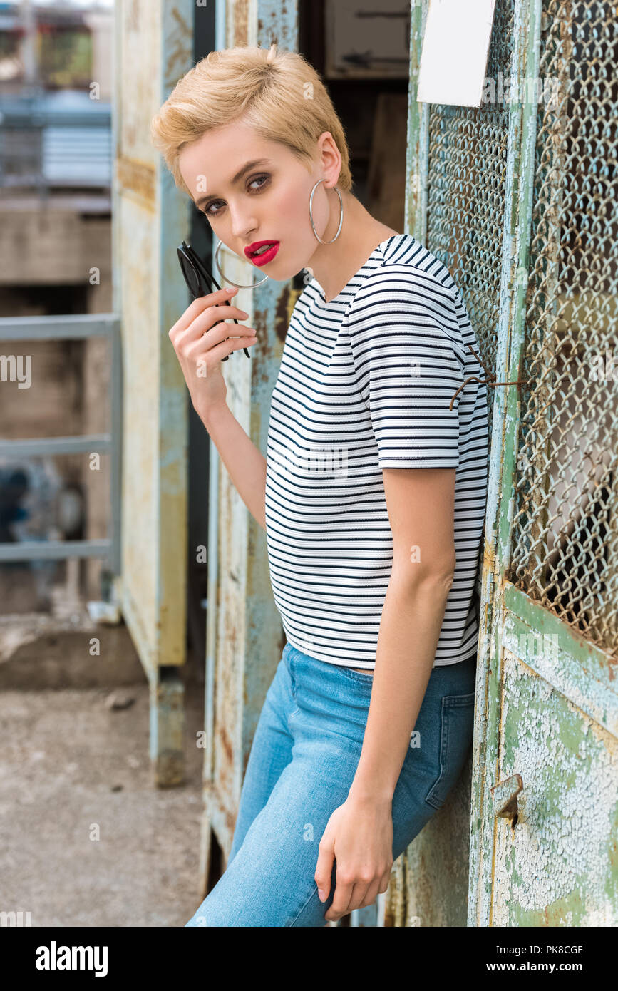 Stylish Girl With Short Hair Holding Sunglasses And Looking At