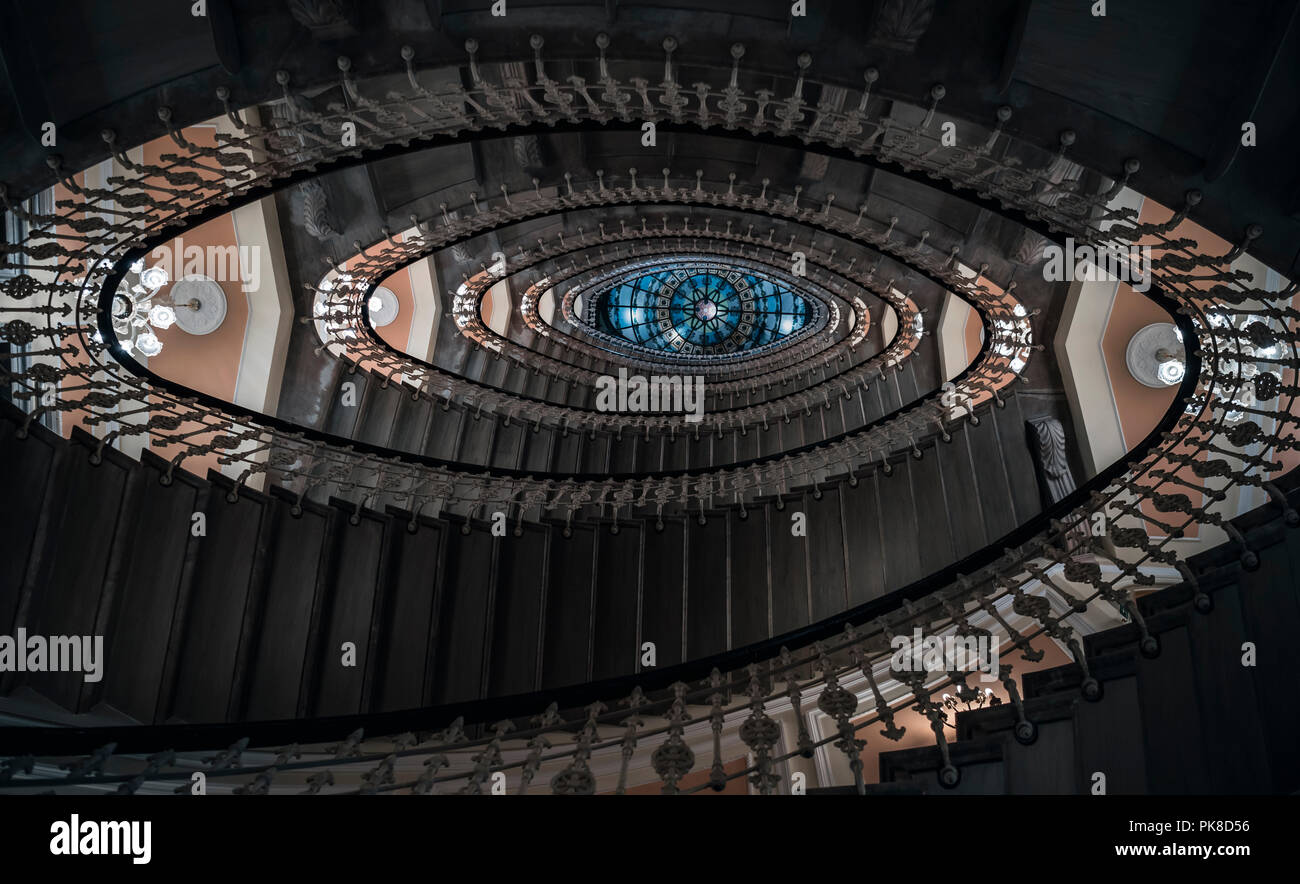 Eye-catching image with staircase design in a spiral form, a pattern of oval figures, illuminated by chandeliers, viewed from under, in Genoa, Italy. Stock Photo