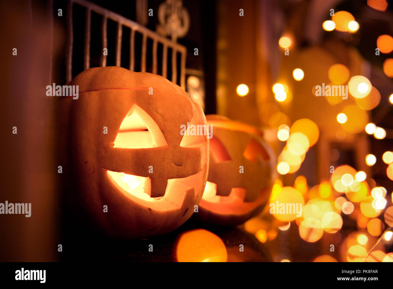 Halloween pumpkins at home on a fireplace with sparkling lights. Cosy autumn background. Stock Photo