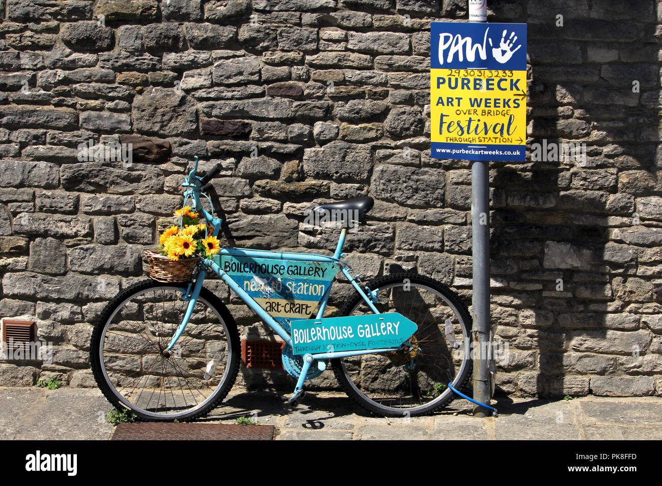 Corfe, England - June 03 2018: Decorated blue bicycle belonging to Boilerhouse Gallery, advertising Purbeck Art Week or PAW Stock Photo