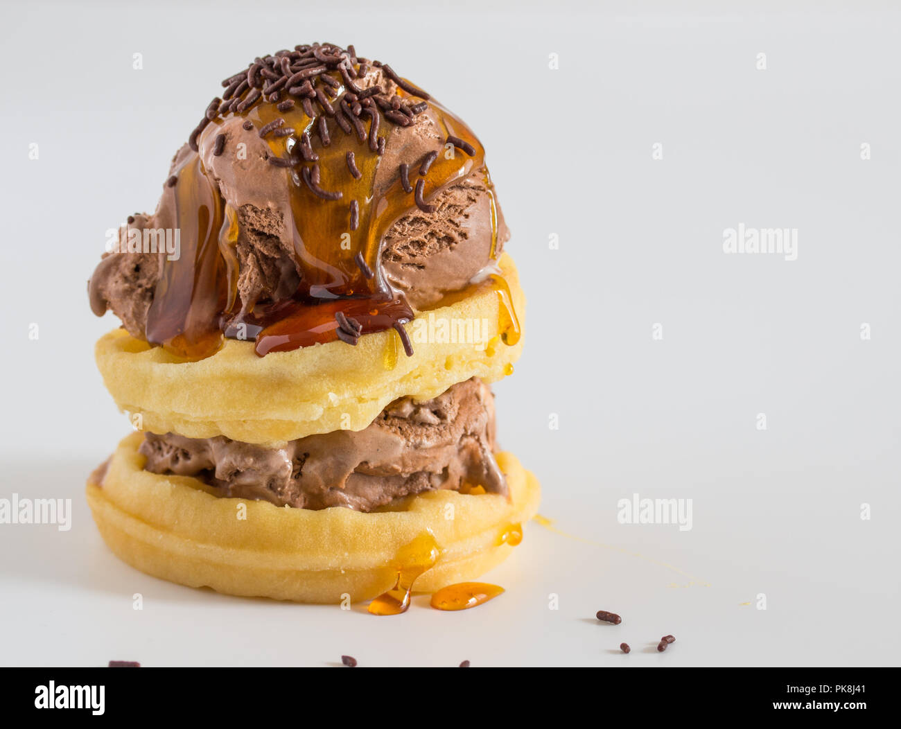 Chocolate ice cream scoop on top of waffles with syrup and chocolate sprinkles over white Stock Photo