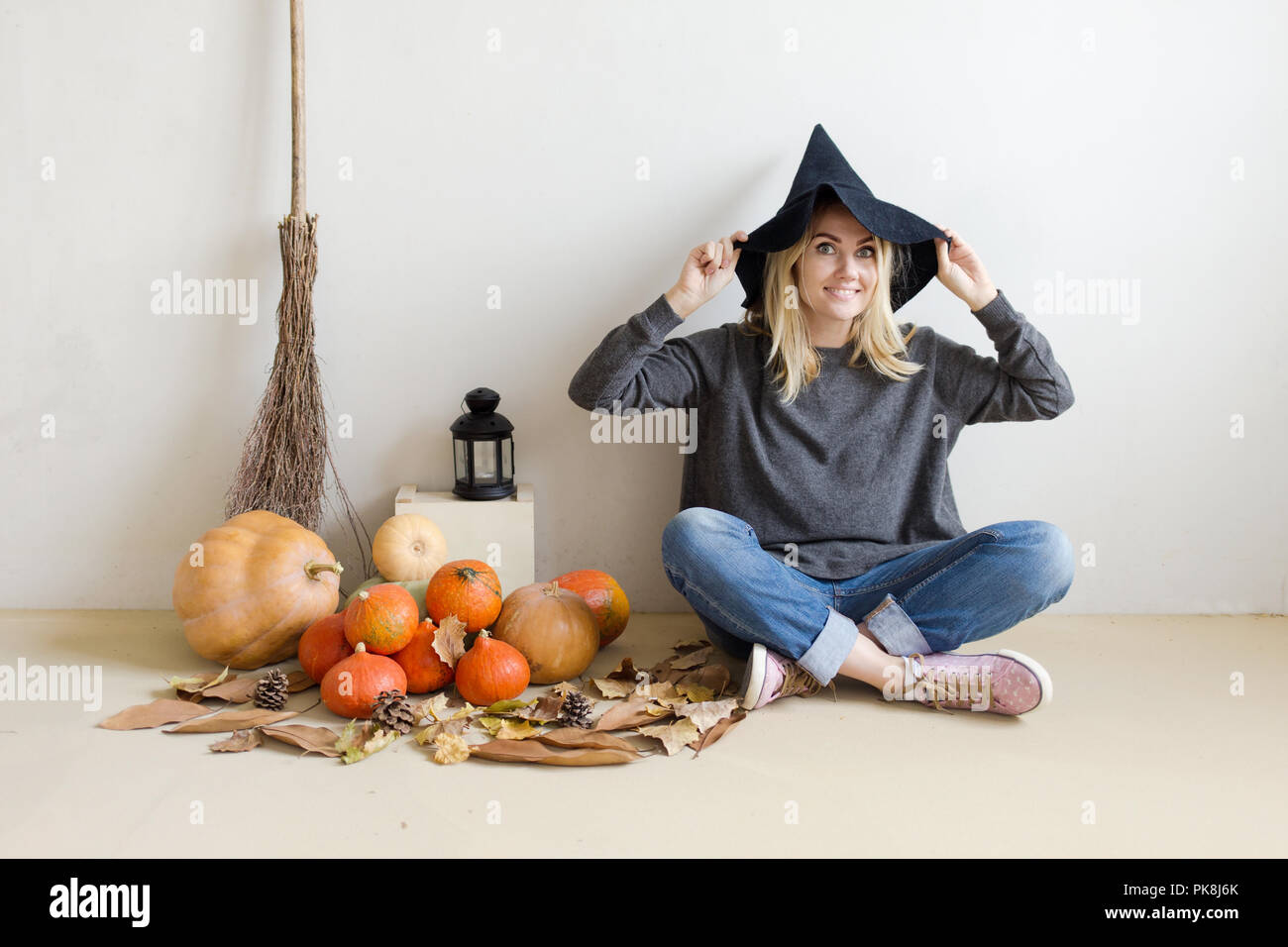 Halloween concept. Beautiful blond girl in a witch hat with pumpkins ...