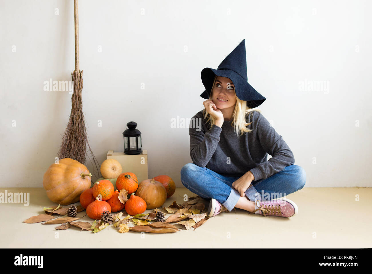 Halloween concept. Beautiful blond girl in a witch hat with pumpkins ...