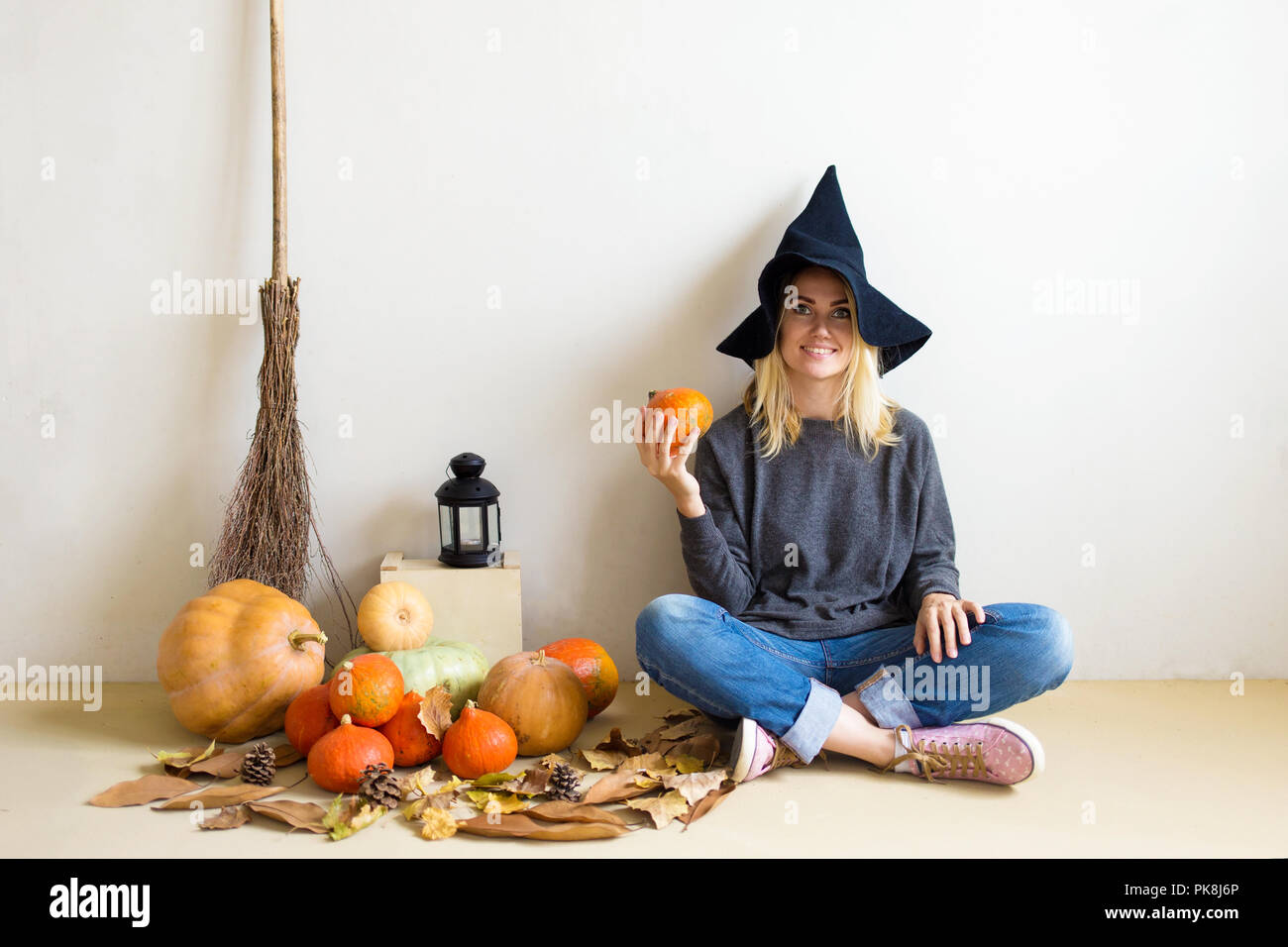 Halloween concept. Beautiful blond girl in a witch hat with pumpkins ...