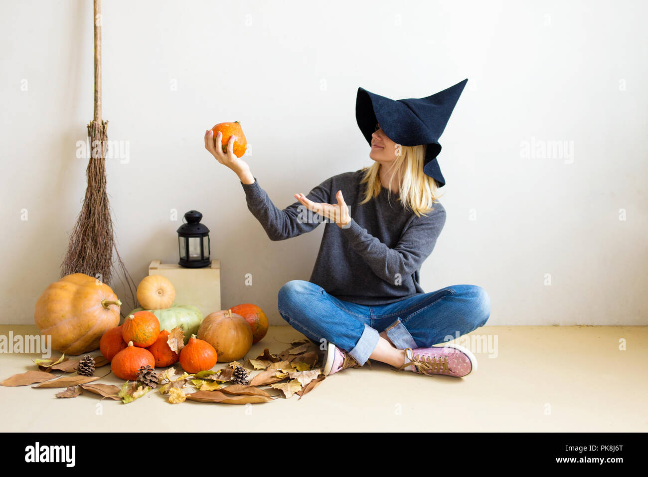 Halloween concept. Beautiful blond girl in a witch hat with pumpkins ...