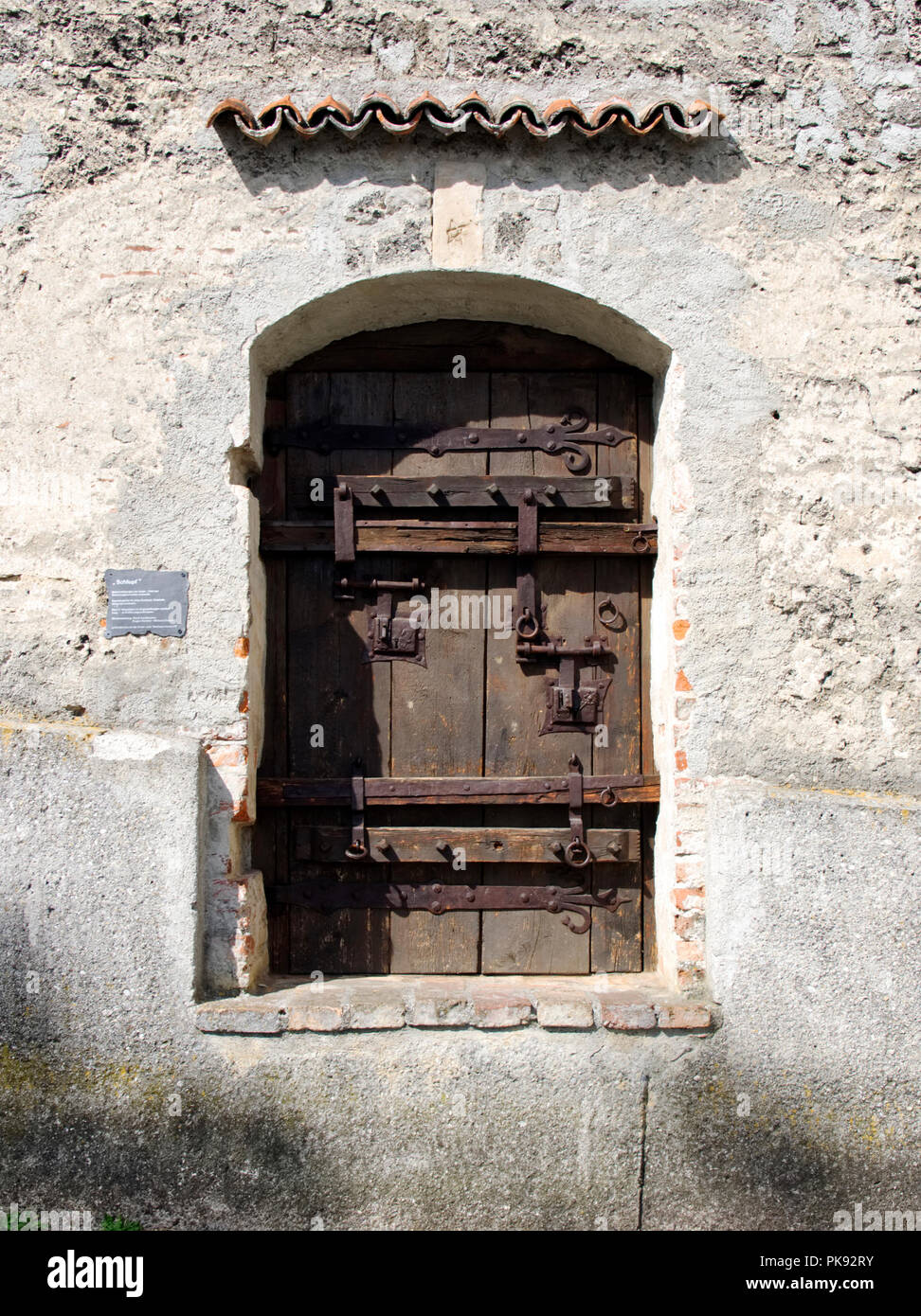 Ancient wooden door with large iron hinges, strapping and bolts in the ...