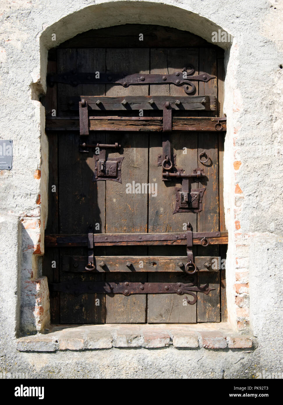 Ancient wooden door with large iron hinges, strapping and bolts in the ...