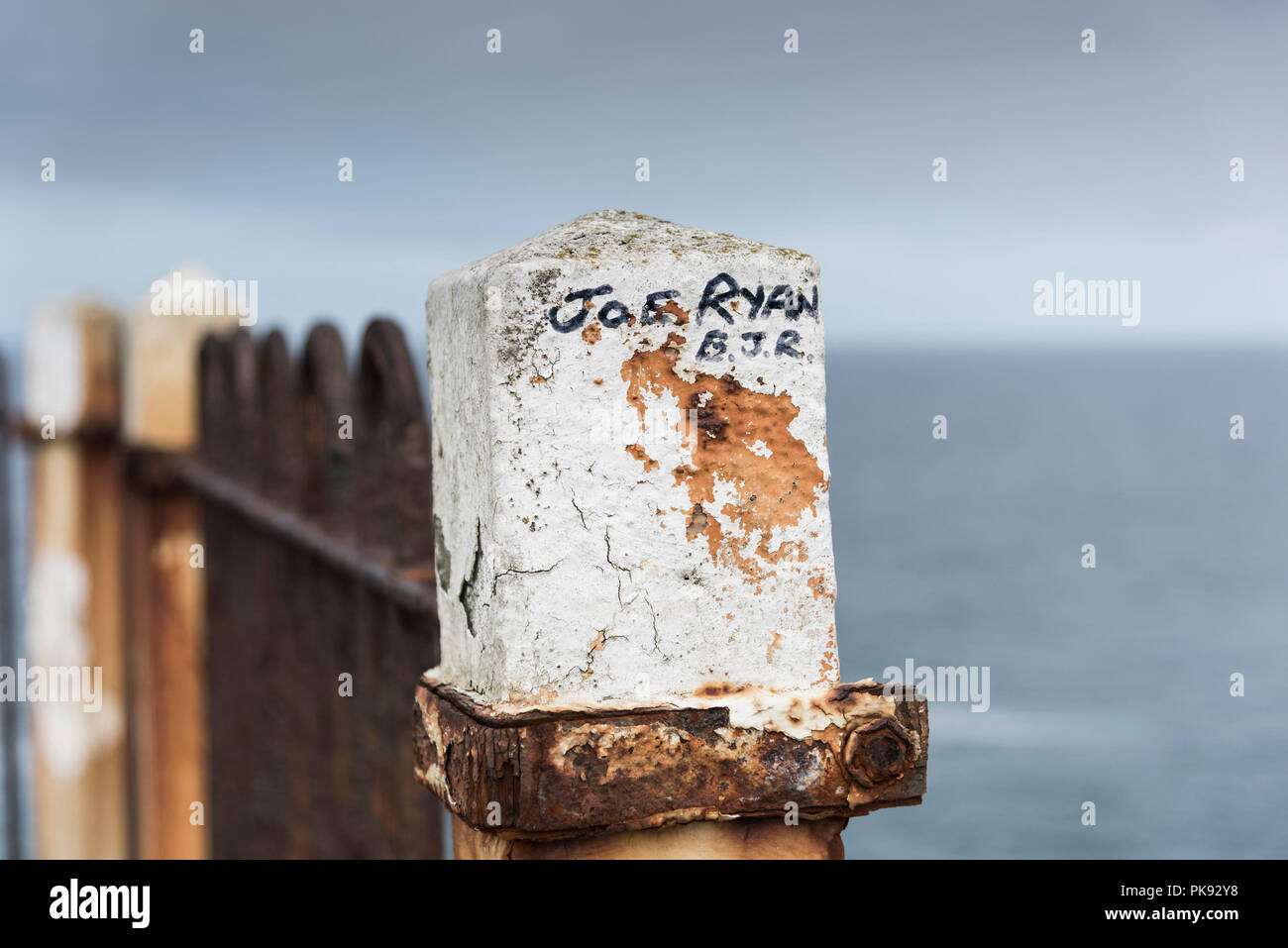 A name written on a weathered concrete fence post. Stock Photo