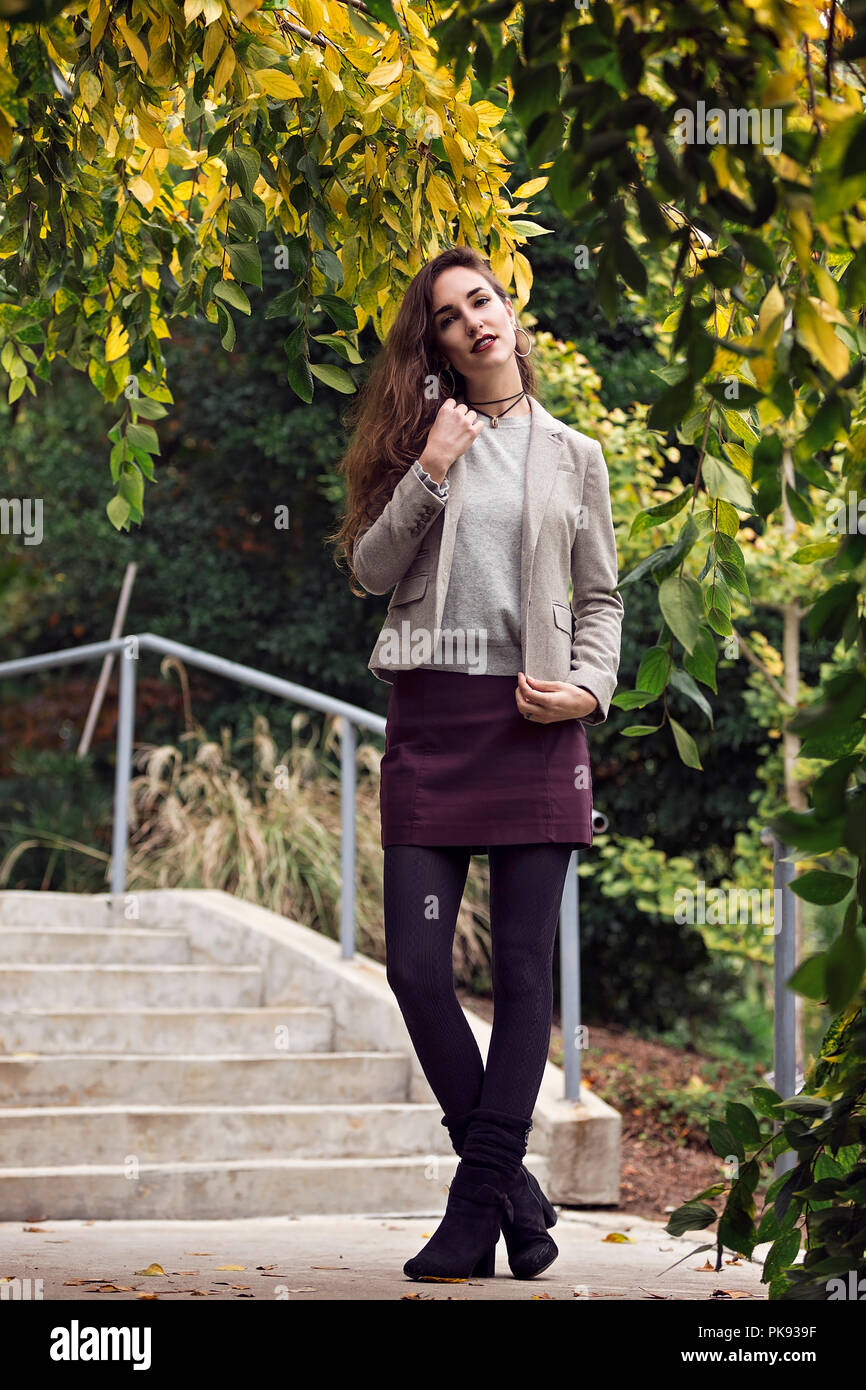 An attractive and well dressed woman standing in front of a set of steps as she poses for the camera Stock Photo