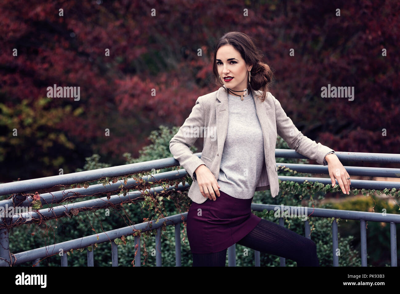 An attractive and well dressed woman standing on an outdoor deck while she poses for the camera Stock Photo