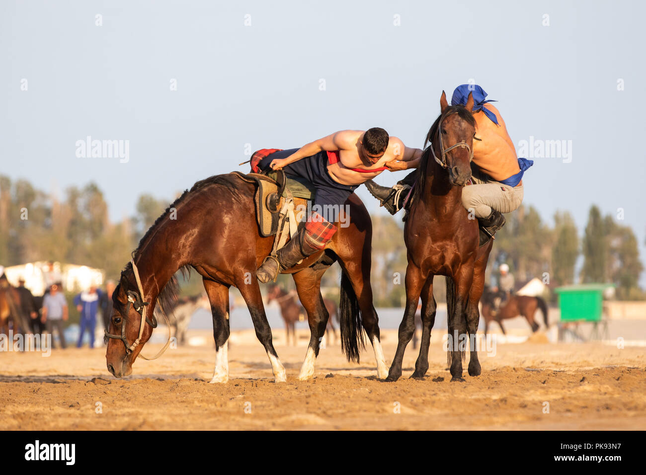Cholpon-Ata city, Kyrgyzstan - Sep 5, 2018: Two men competing in er-enish (traditional Kyrgyz horsemen wrestling) match during 2018 World Nomad Games. Stock Photo