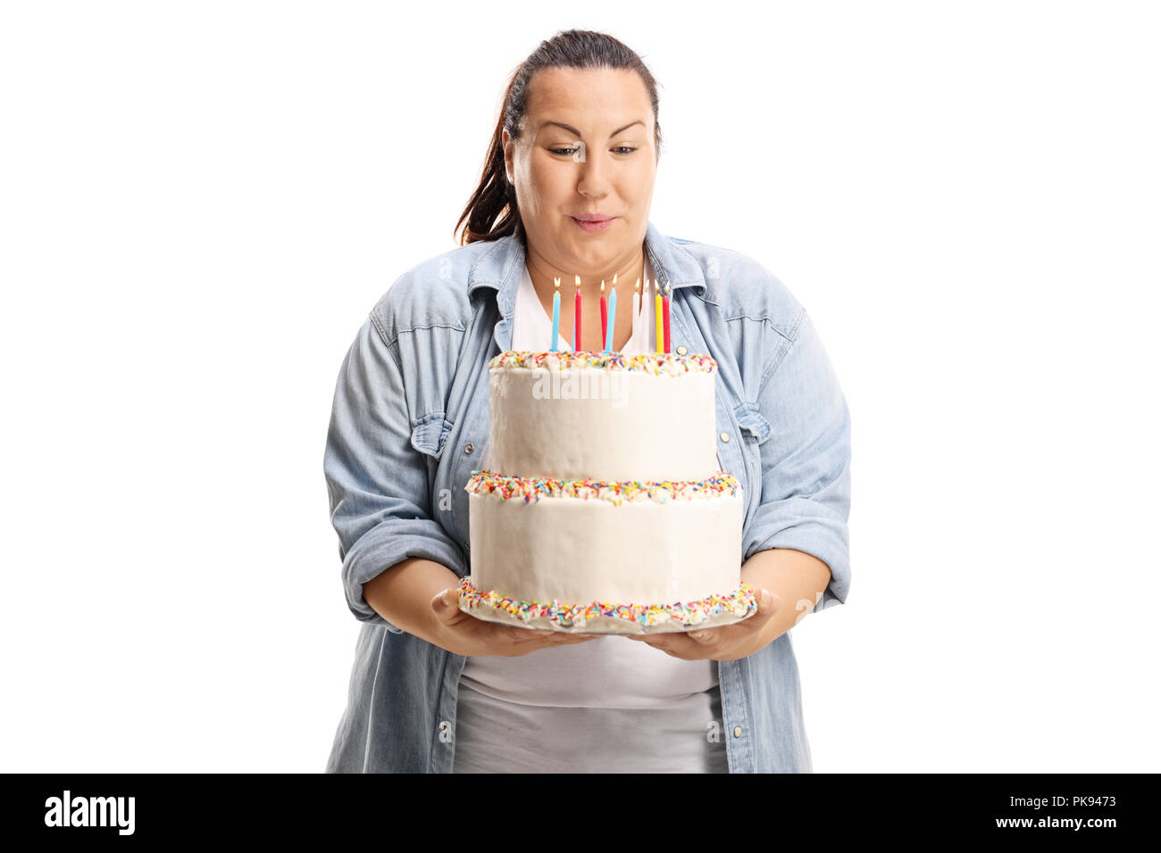 Overweight woman blowing candles on a birthday cake isolated on white background Stock Photo