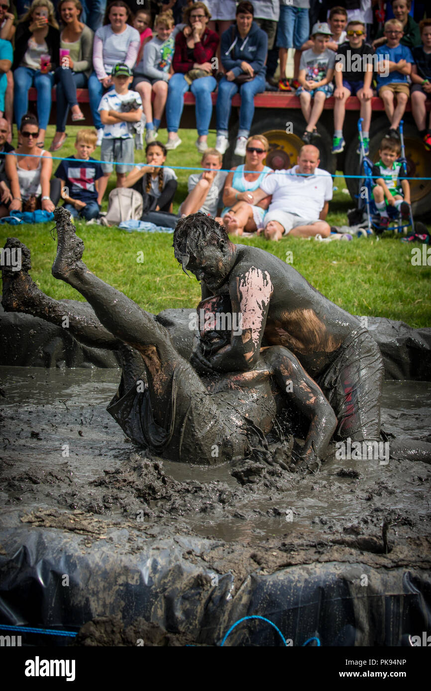 Two men mud wrestling at a mud fighting competition at The LowLand Games in Thorney Somerset Stock Photo