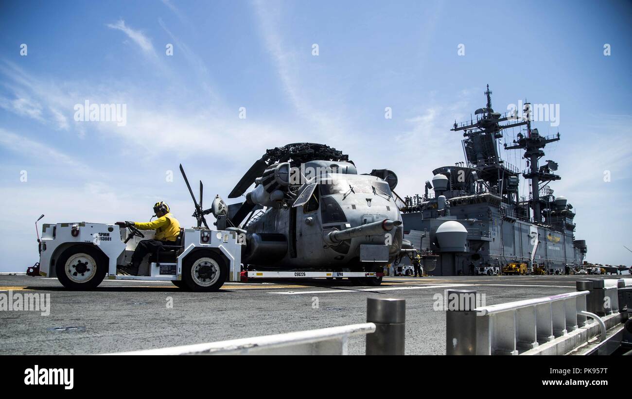 MINDANAO SEA - U.S. Marines with Marine Medium Tiltrotor squadron (VMM) 166 Reinforced, 13th Marine Expeditionary Unit (MEU), and U.S. Navy Sailors with the Essex Amphibious Ready Group (ARG) move a CH-53E Super Stallion from VMM-166 into position for takeoff aboard the Wasp-class amphibious assault ship USS Essex (LHD 2), during search and rescue operations for a missing Marine attached to the 13th MEU while on a regularly scheduled deployment of the Essex ARG and 13th MEU, August 12, 2018, August 12, 2018. The Essex ARG/ 13th MEU is currently deployed to the 7th fleet area of operations. (U. Stock Photo