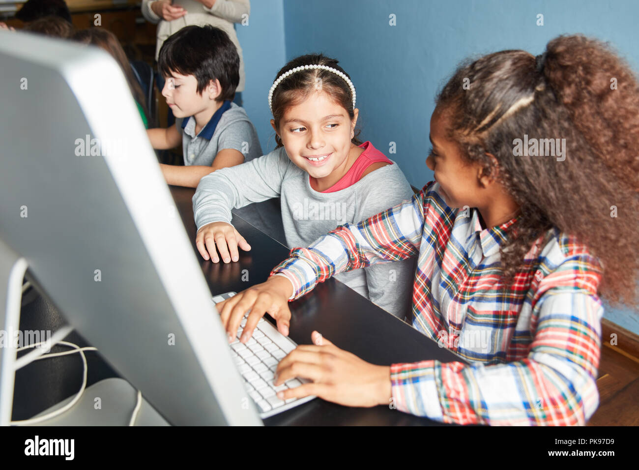 In elementary school computer science girls learn together at the computer Stock Photo