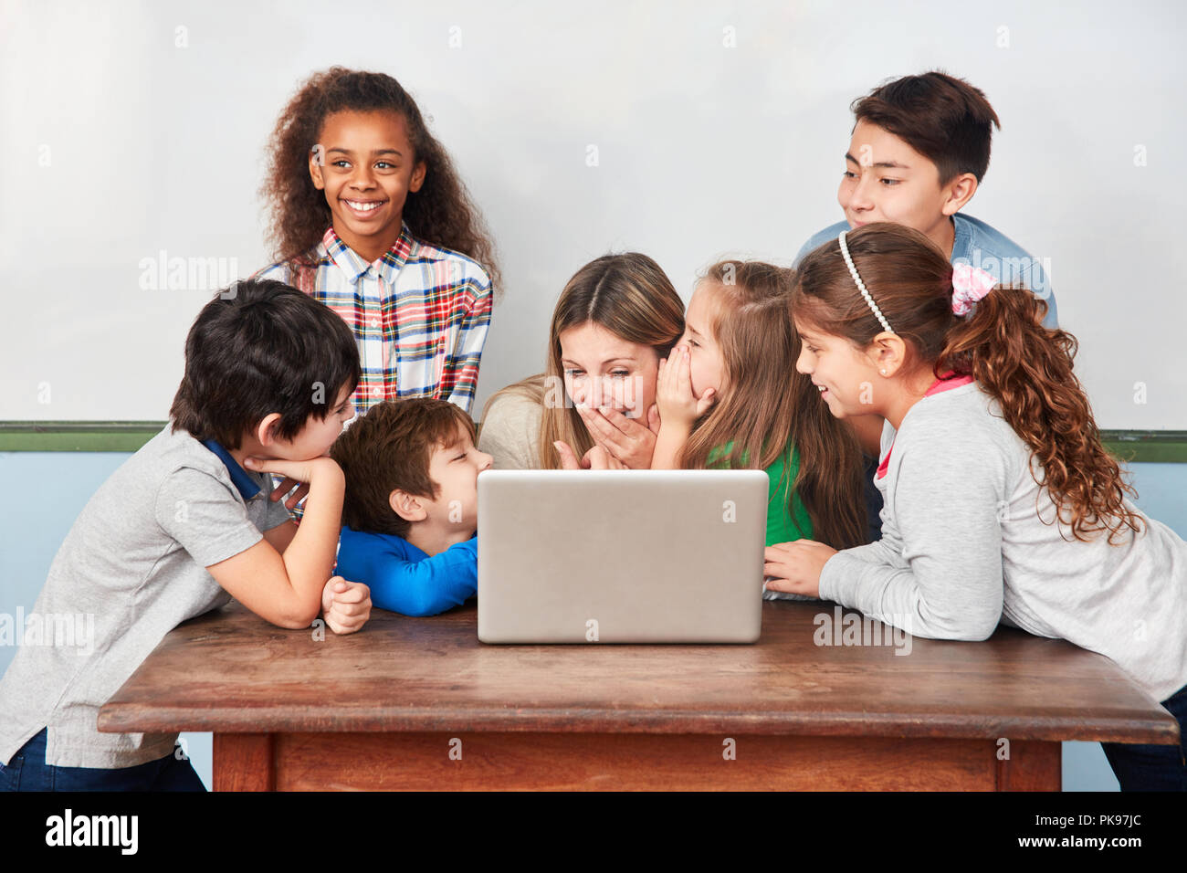 Group of kids laughing and joking with teacher in computer lesson Stock Photo