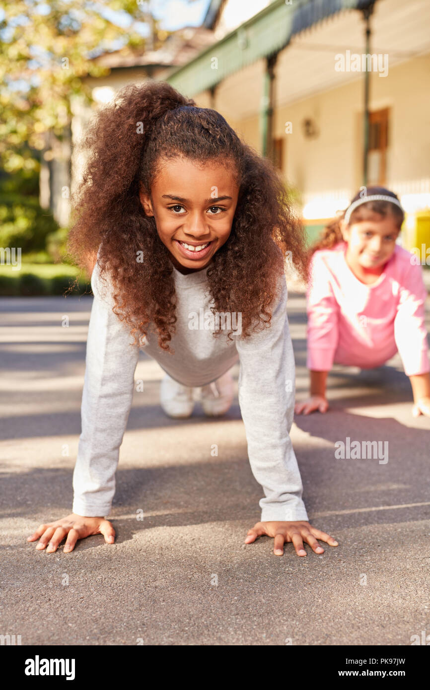 Girl enjoys school physical education and does push-ups Stock Photo