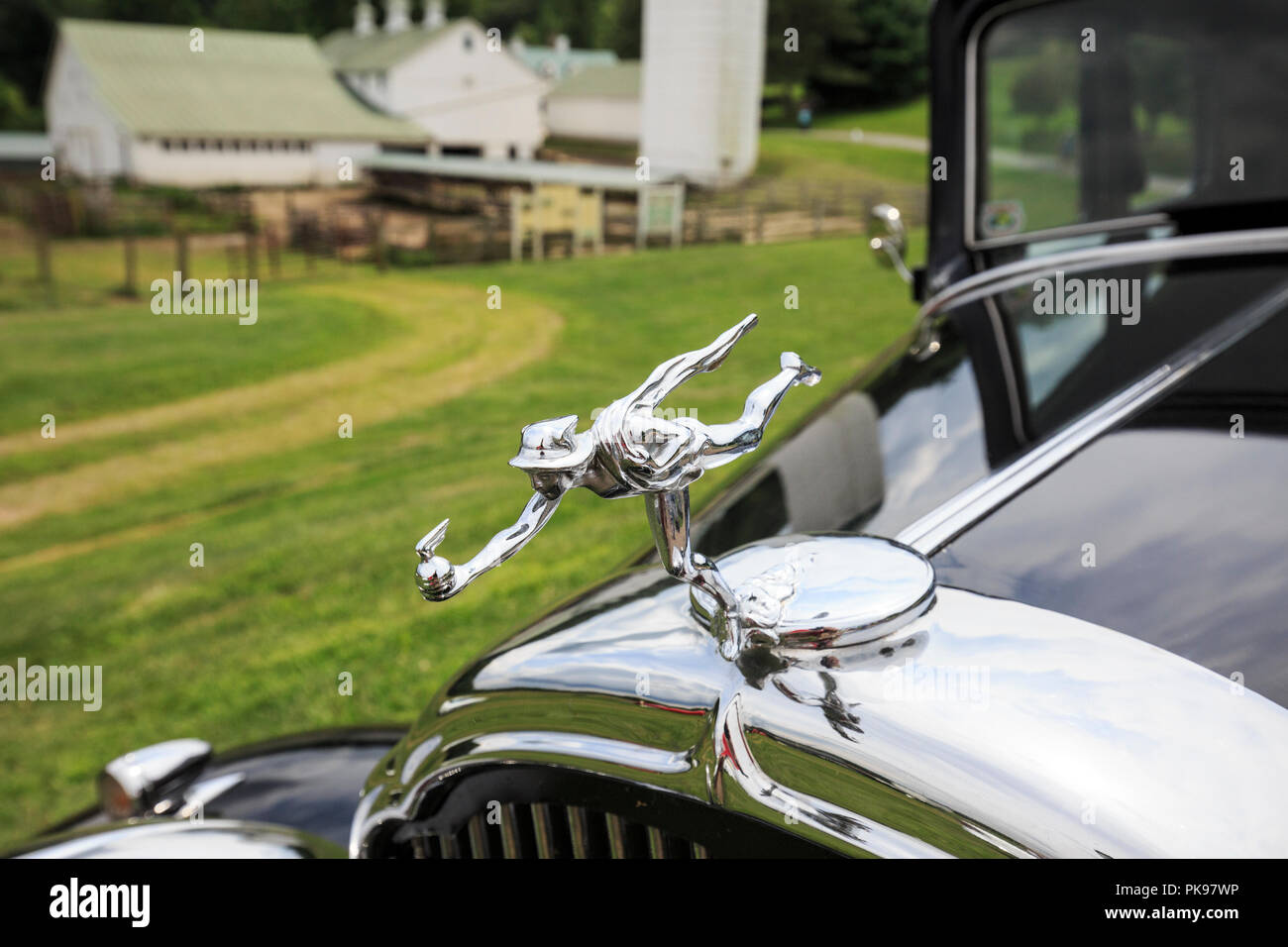 1932 Buick Victoria Coupe hood ornament with old farm in the background. Stock Photo