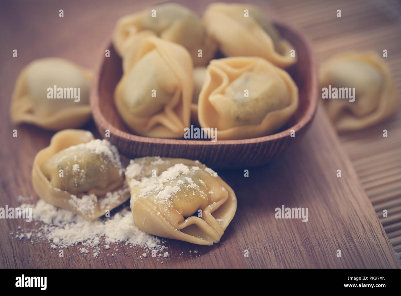 Italian Tortelloni made of spinach with flour on wooden surface Stock Photo