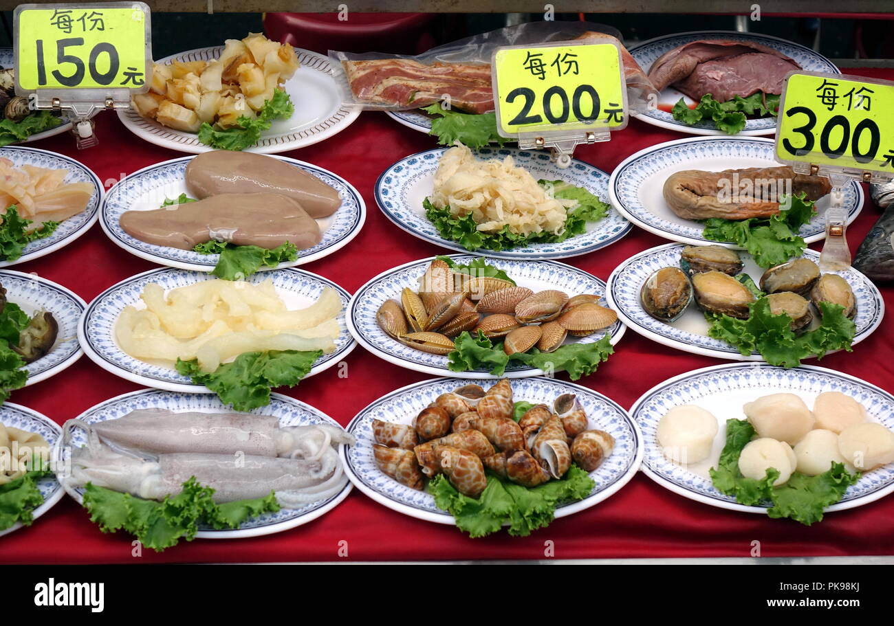 A nightmarket food stall displays a choice of raw seafood dishes Stock Photo