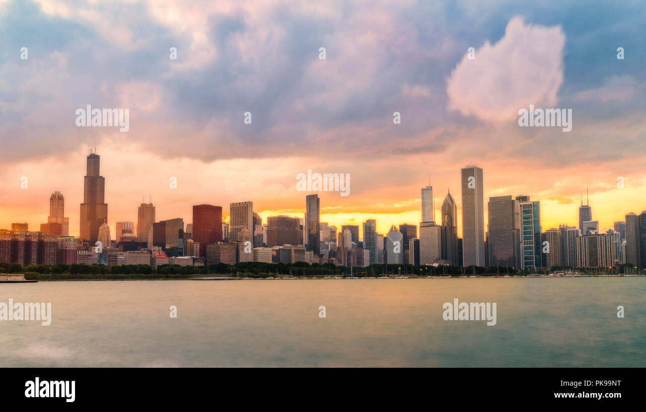 Chicago skyline at sunset with cloudy sky and reflection in water. Stock Photo