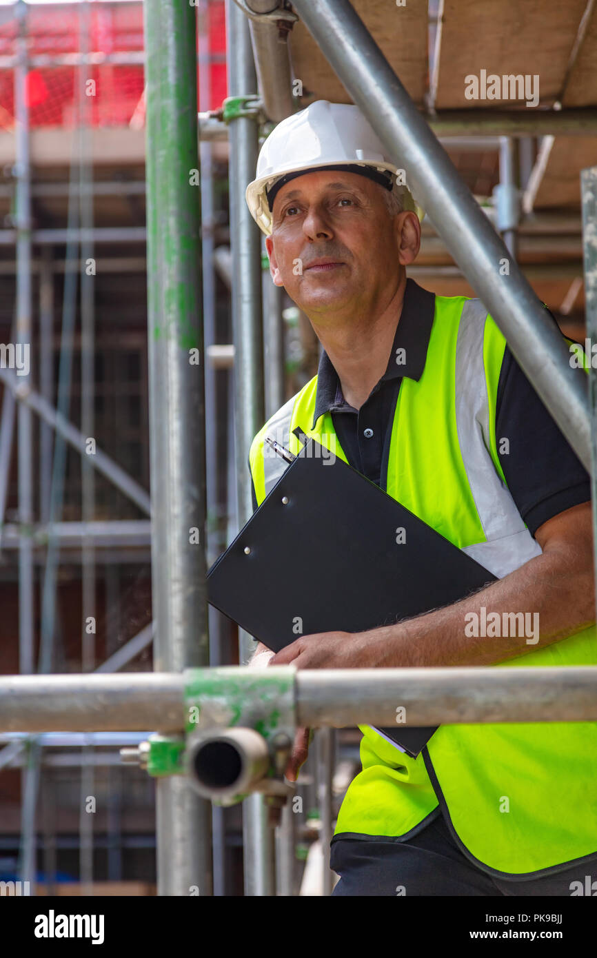 Male builder foreman, construction worker or site manager holding a