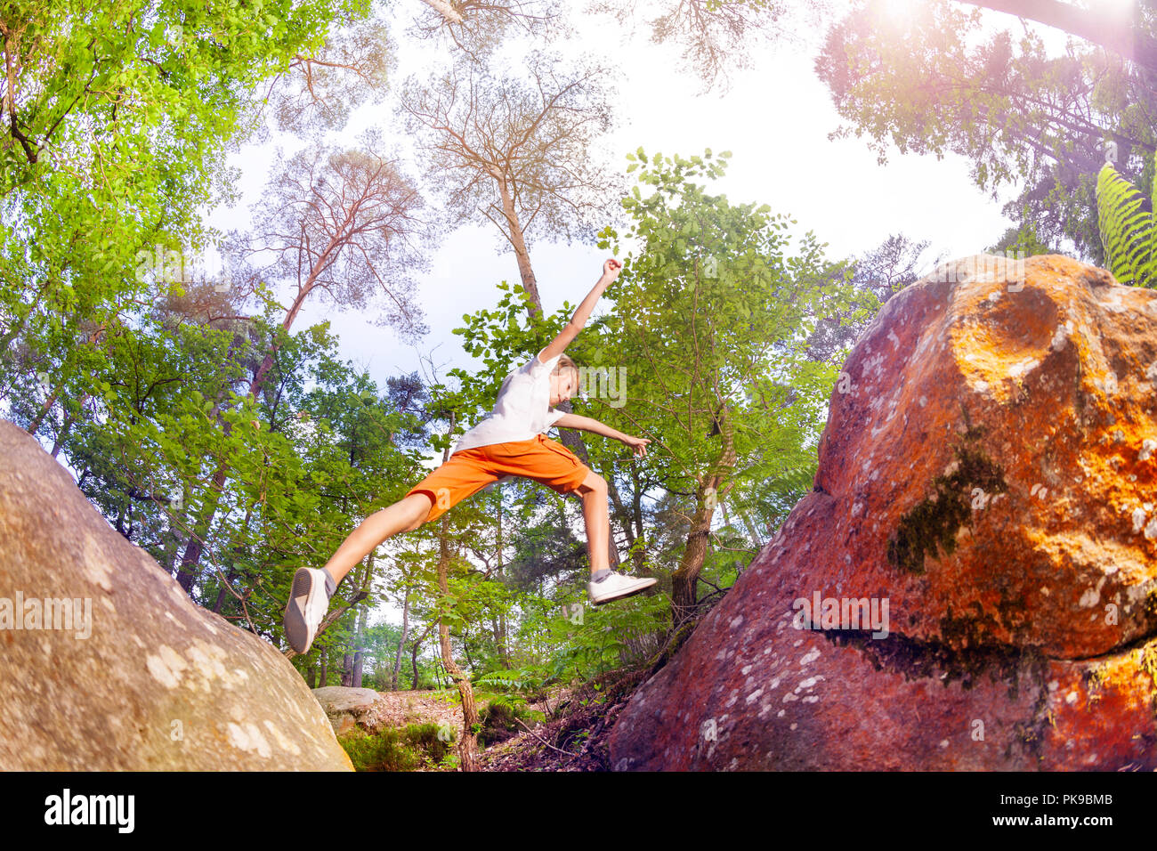 Boy in the process of jumping from stone to other Stock Photo - Alamy