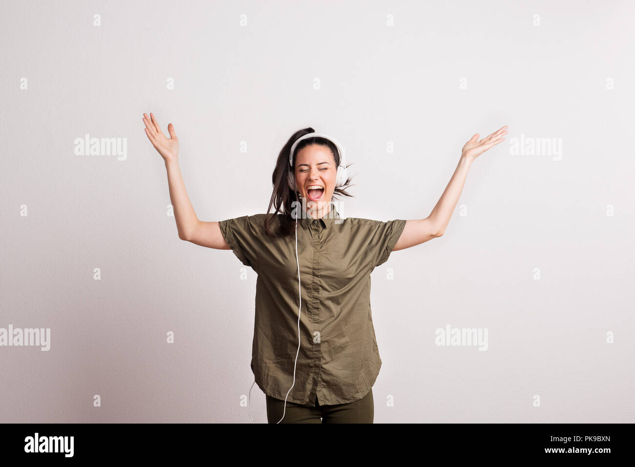 Cheerful young beautiful woman with headphones, listening to music and ...