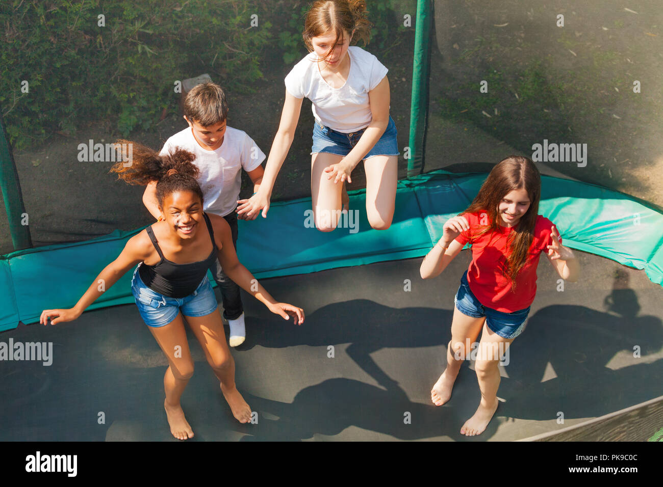 Four happy friends bouncing on outdoor trampoline Stock Photo Alamy
