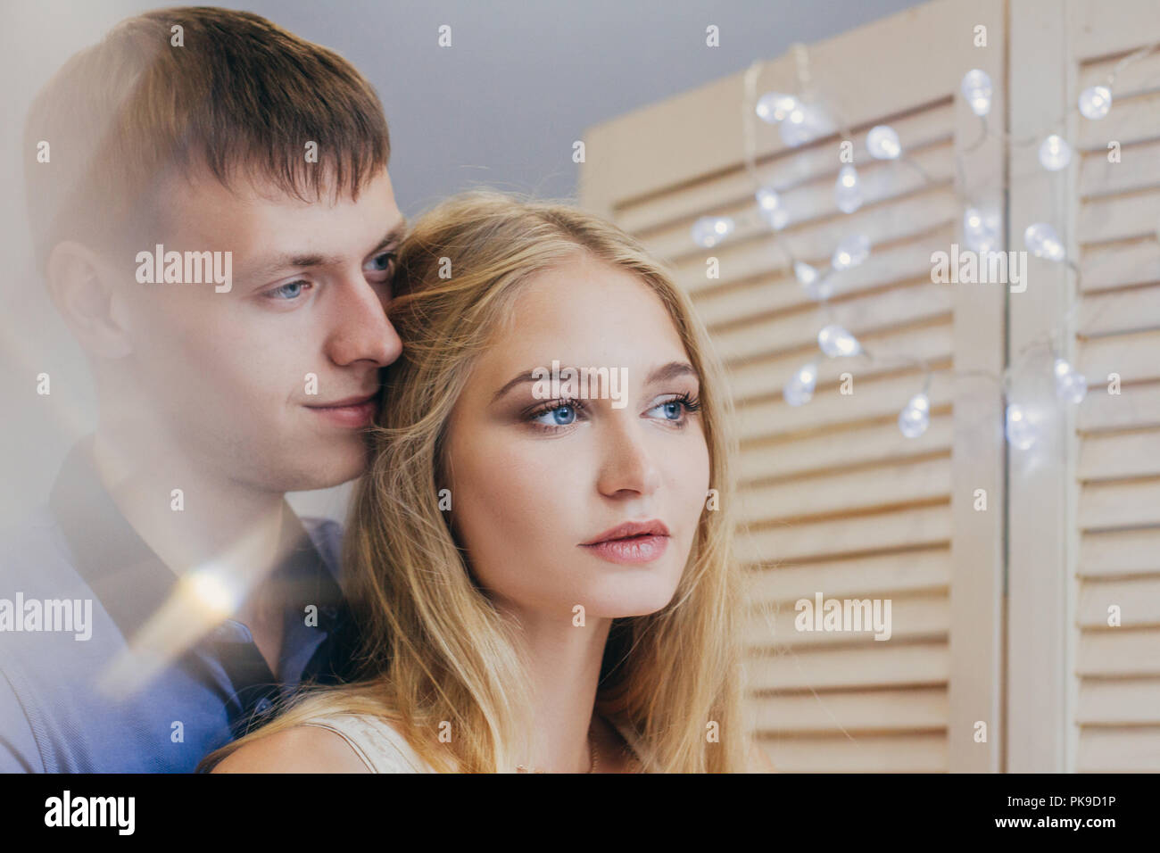 Beautiful loving couple looking out the window. Guy and girl cuddling ...