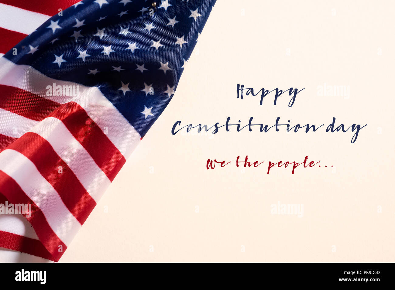 closeup of a flag of the United States and the text happy constitution day against an off-white background Stock Photo