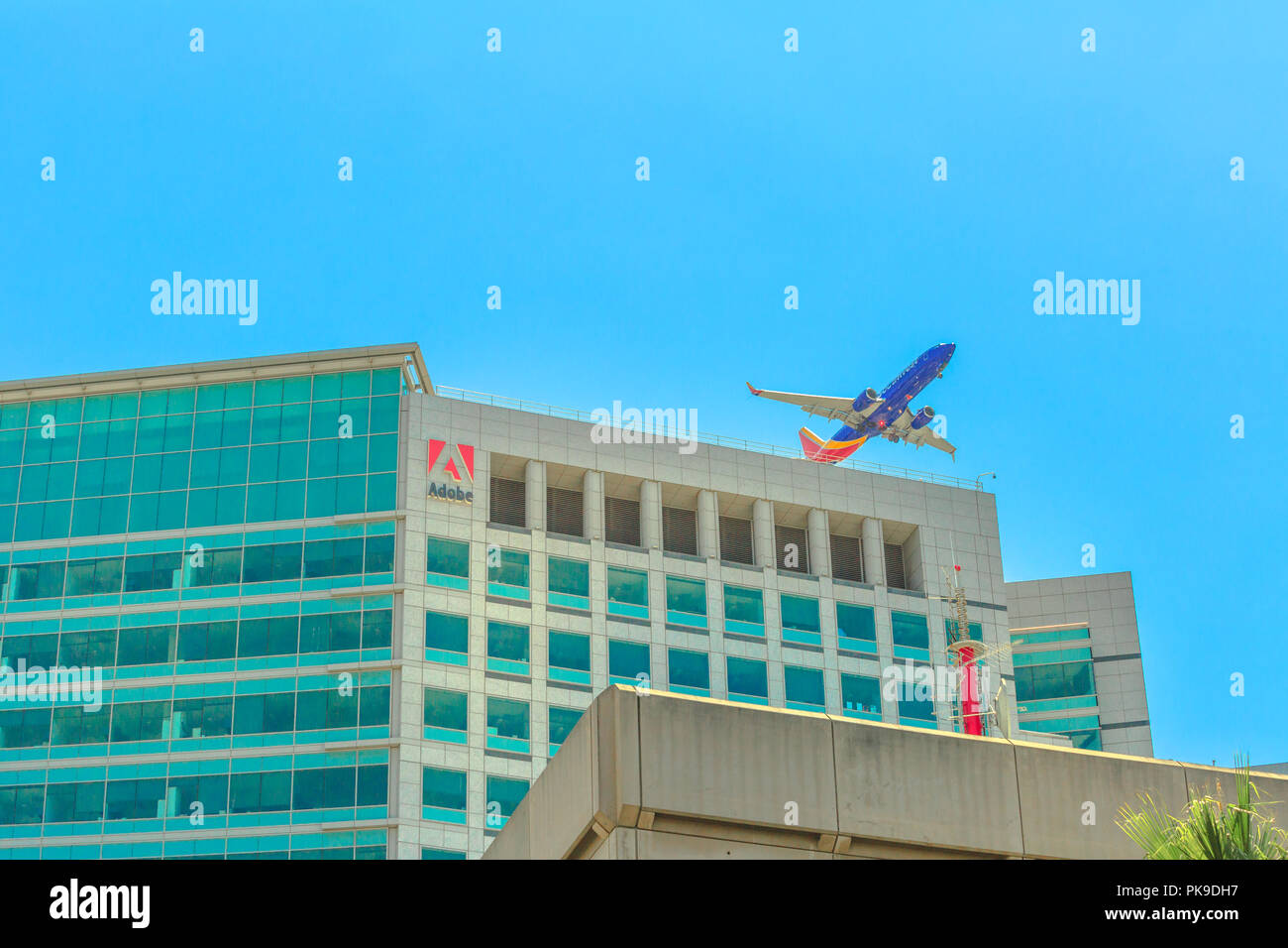 San Jose, CA, United States - August 12, 2018: Adobe headquarters skyscraper in Silicon Valley, with an airplane flying above from the close international airport Norman Y. Mineta of San Jose. Stock Photo