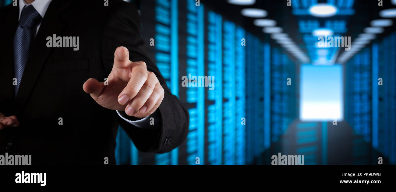 Businessman working with VR wide blank screen computer on server room in background. Stock Photo