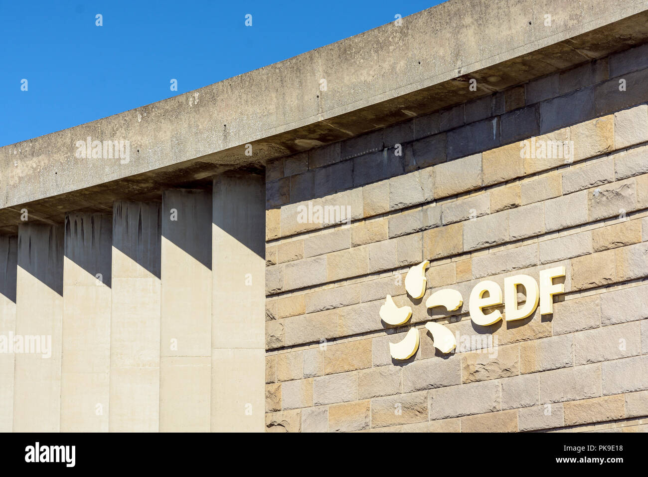 Logo of french public electricity utility company EDF on the stone wall of a building of the Rance tidal power station near Saint-Malo in Brittany. Stock Photo