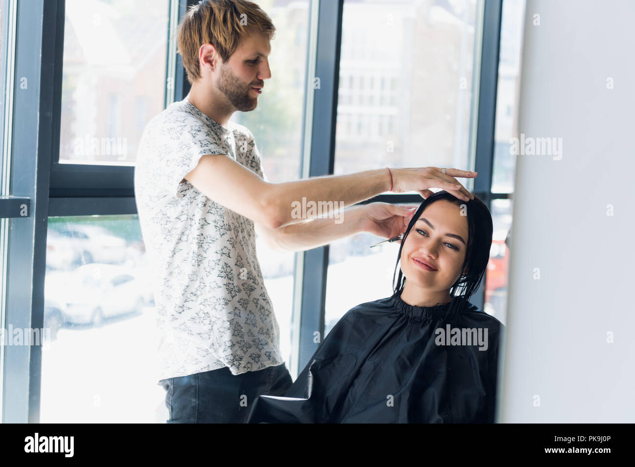 Young beautiful woman having her hair cut at the hairdresser's. Enjoying the process of making a new hair style. Stock Photo
