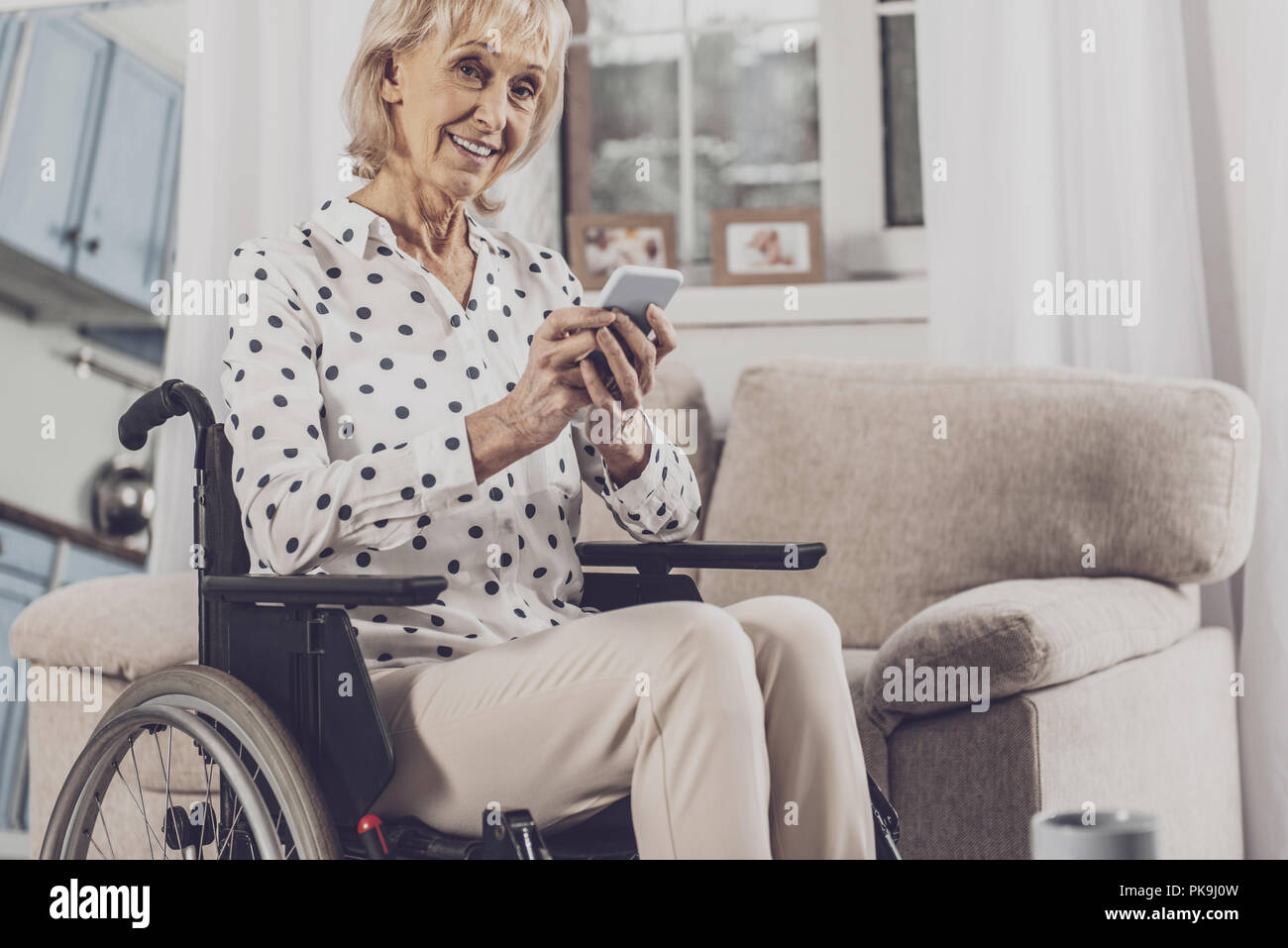 Blue-eyed woman holding her phone sitting in wheelchair Stock Photo - Alamy