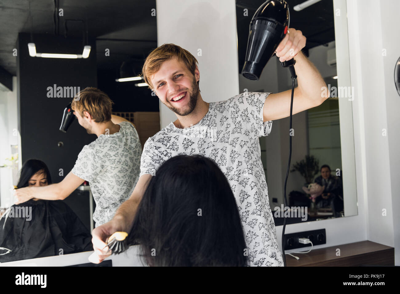 Portrait of happy hairdresser holding comb and blow dryer in salon Stock Photo
