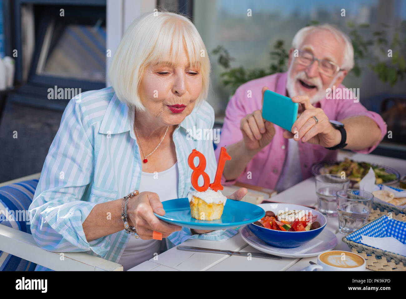 Positive aged woman holding a plate with birthday cake Stock Photo - Alamy