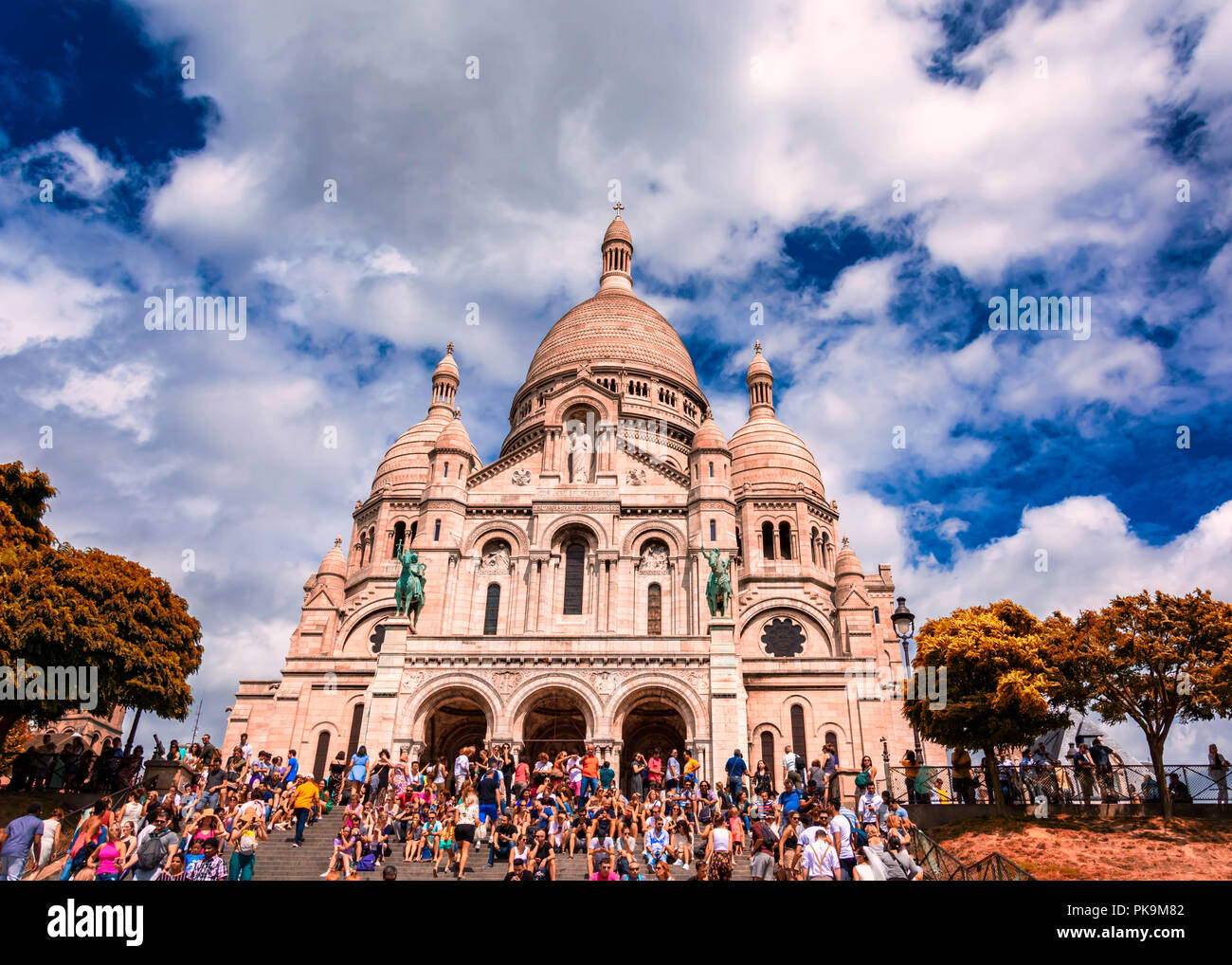 sacre-coeur limestone Cathedral montmarte , paris,france during sunnyday with green conopy and tourists sitting on steps Stock Photo