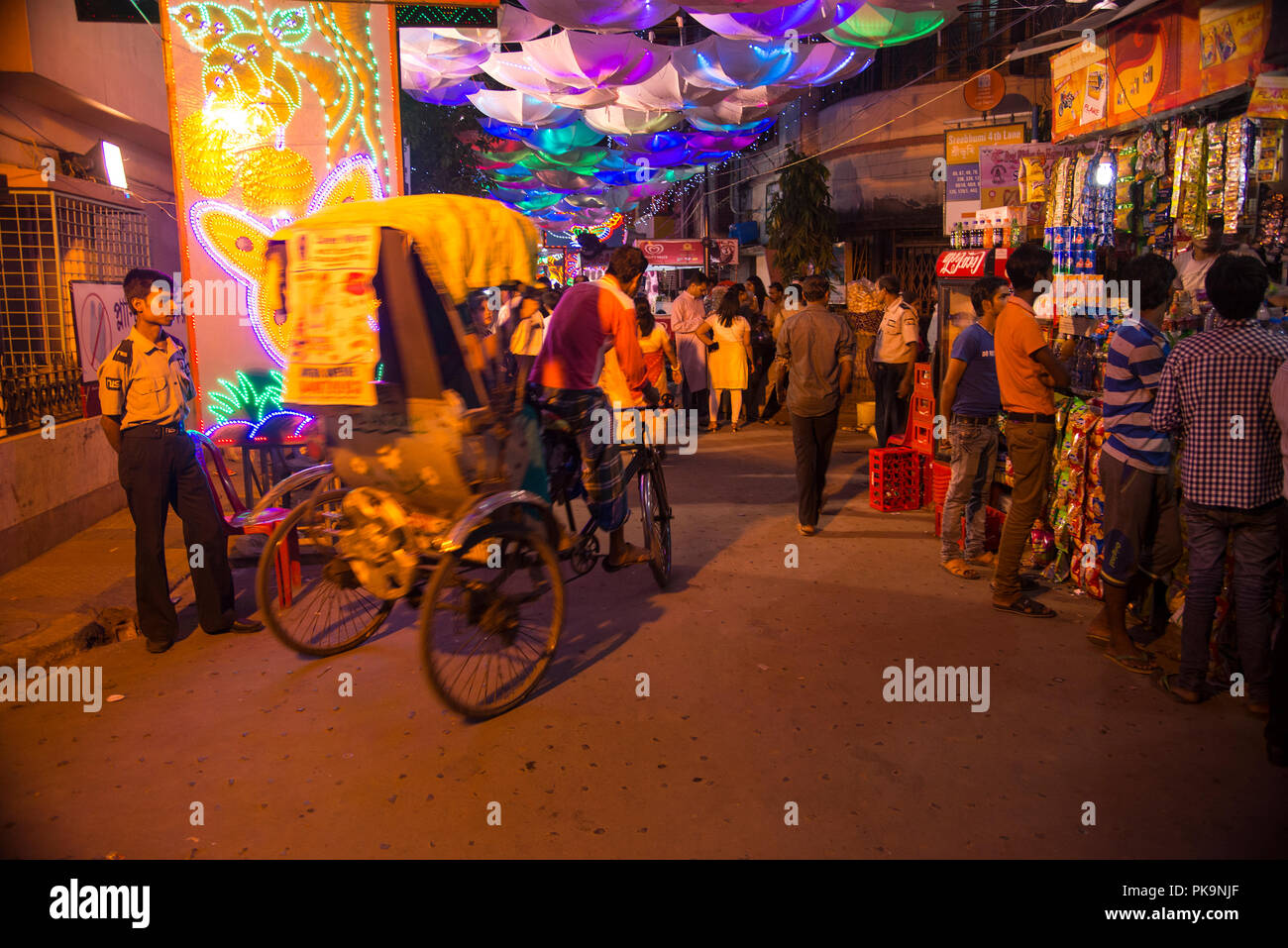 Durga puja,traffic,a cycle rickshaw,in the passage,to, Sreebhumi,Durga Puja,pandal,under.coloured,lighted, umbrella,stalls,people,venders,Kolkata,Indi Stock Photo