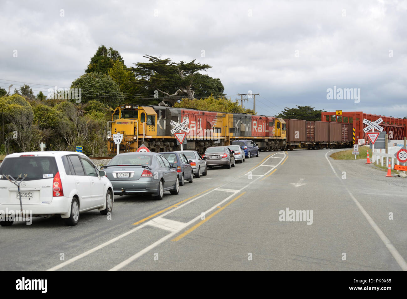 TARAMAKAU RIVER, NEW ZEALAND, NOVEMBER 18, 2017: A freight train holds up traffic at the historic road-rail bridge across the Taramakau River near Greymouth, New Zealand Stock Photo