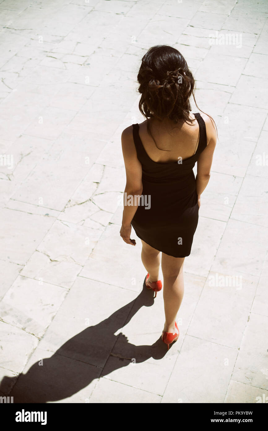 High angle view of a woman in black dress walking away outdoors Stock Photo