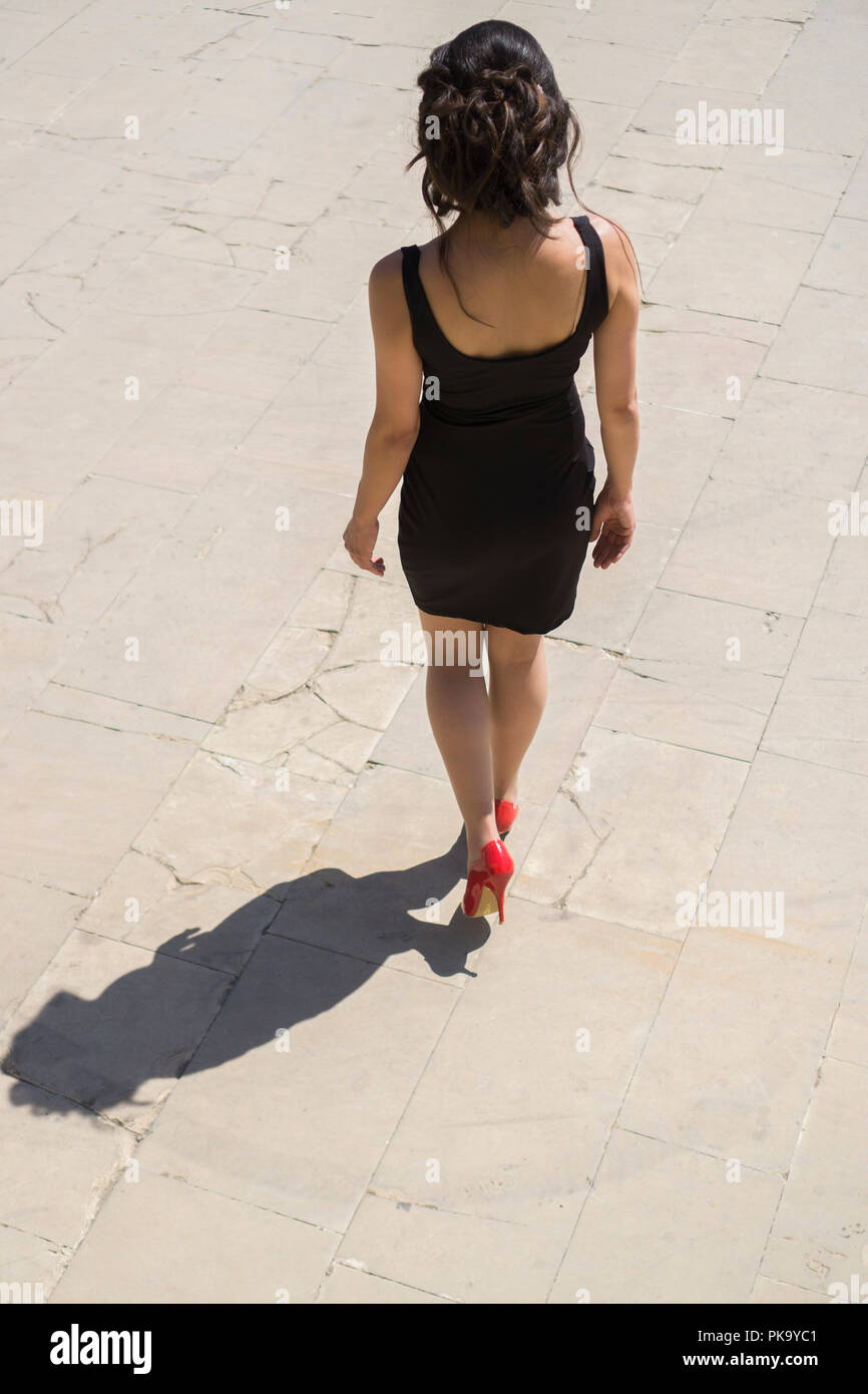 High angle view of a woman in black dress walking away outdoors Stock Photo