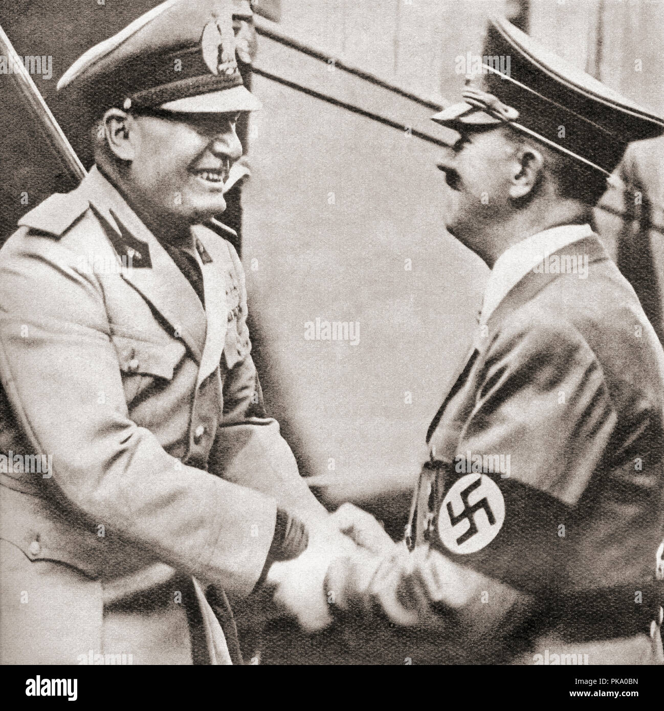 Adolf Hitler, right, welcomes Benito Mussolini in Kufstein, Austria on the occasion of the Munich Conference, 1938.   Adolf Hitler,1889 – 1945. German politician, demagogue, Pan-German revolutionary, leader of the Nazi Party, Chancellor of Germany, and Führer of Nazi Germany from 1934 to 1945.  Benito Amilcare Andrea Mussolini, 1883 – 1945.  Italian politician, journalist, leader of the National Fascist Party and Italian Prime Minister from 1922 to 1943.  From These Tremendous Years, published 1938. Stock Photo