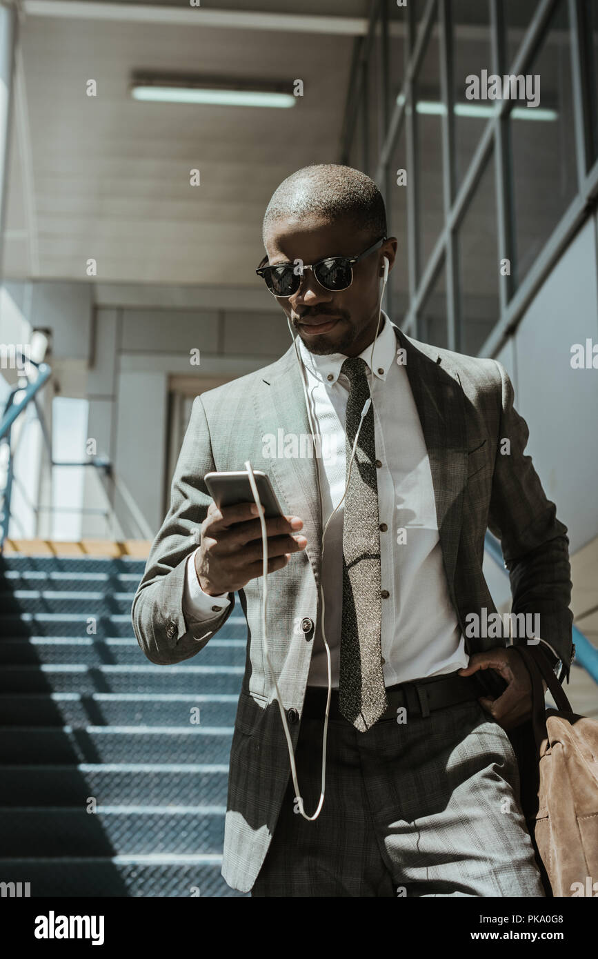 Stylish confident businessman using smartphone while walking on stairs Stock Photo