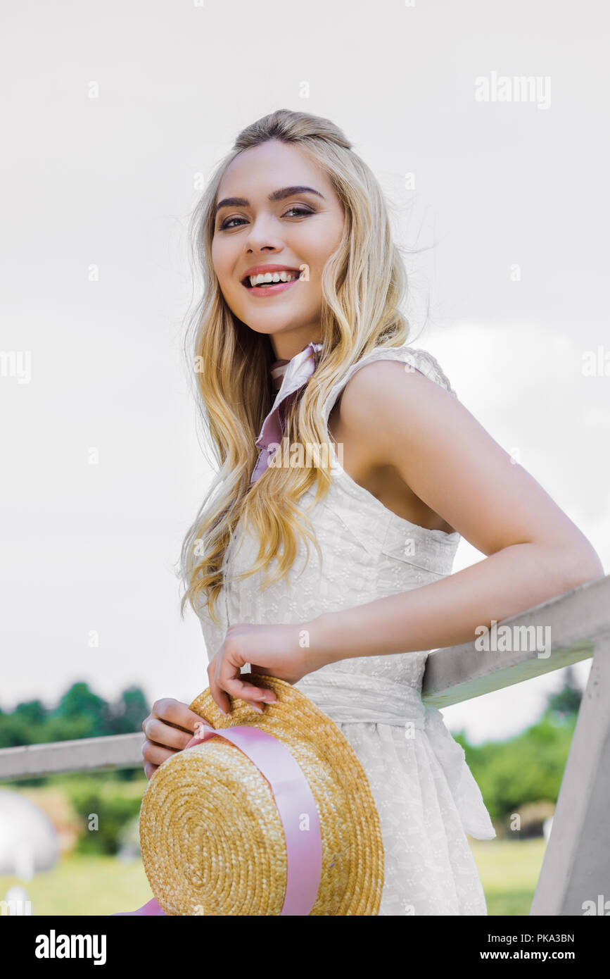 low angle view of attractive smiling blonde girl wearing white